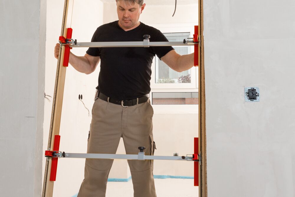 Fitter installs door with door frame struts TU