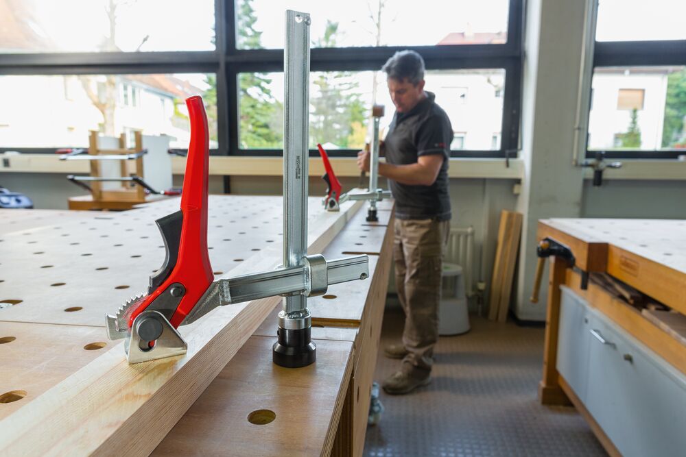 Spannelement für Multifunktionstisch mit 20 mm Lochdurchmesser spannt eine Holzlatte auf dem Multifunktionstisch
